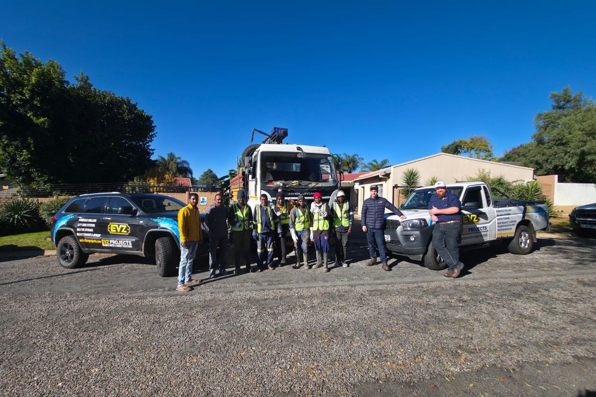 EVZ Projects team standing with branded vehicles and drilling equipment