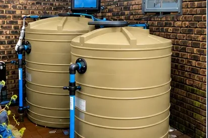 Standard water backup system — 2500L tank with 0.75kW booster pump installed against a brick wall
